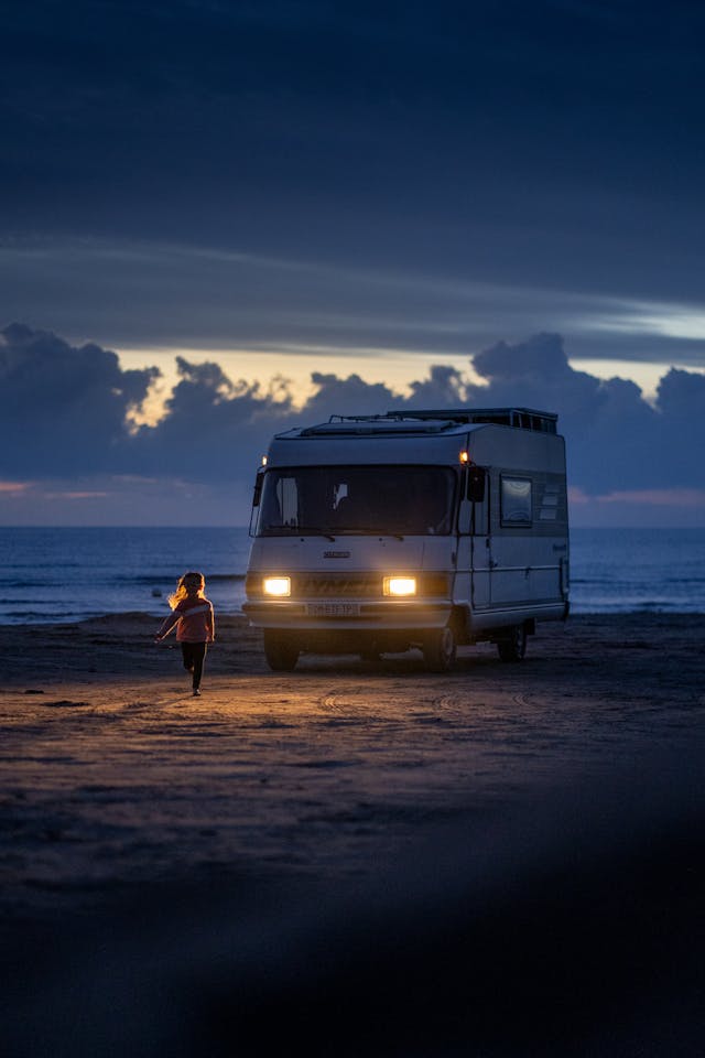 a child running on the beach in front of a parked motorhome