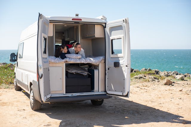 a-couple-lying-in-a-bed-inside-a-rv