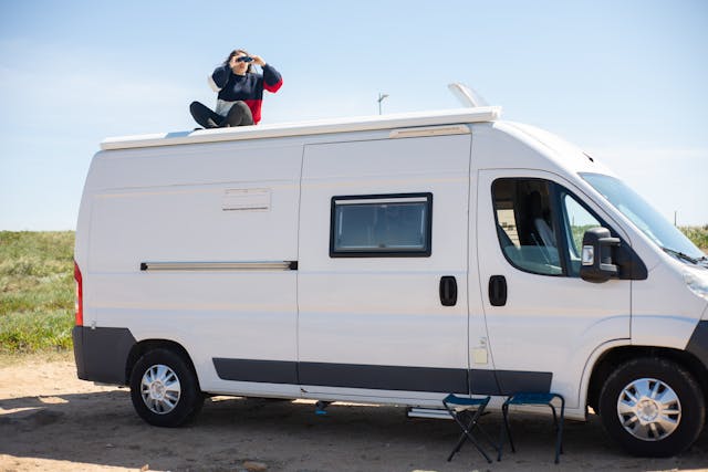 a-woman-using-binoculars-while-sitting-on-top-of-a-rv