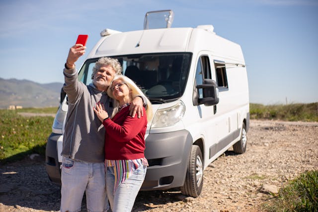 an elderly couple taking a selfie beside their rv