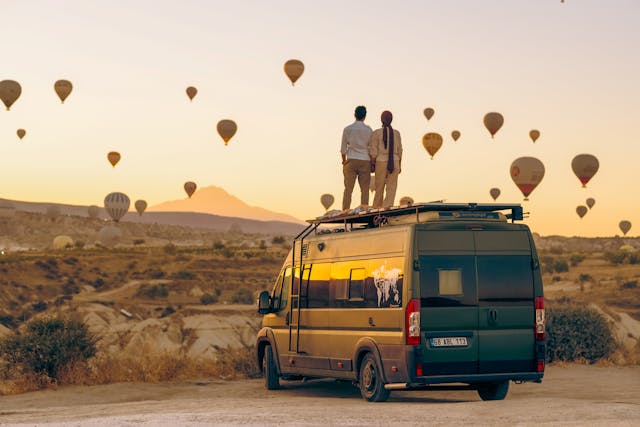 couple watching rising hot air balloons from the roof of an rv van